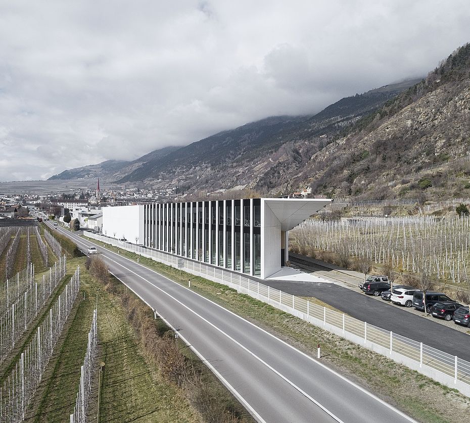 Vista aerea edificio moderno con facciata bianca nella Val Venosta sudtirolese presso frutteti