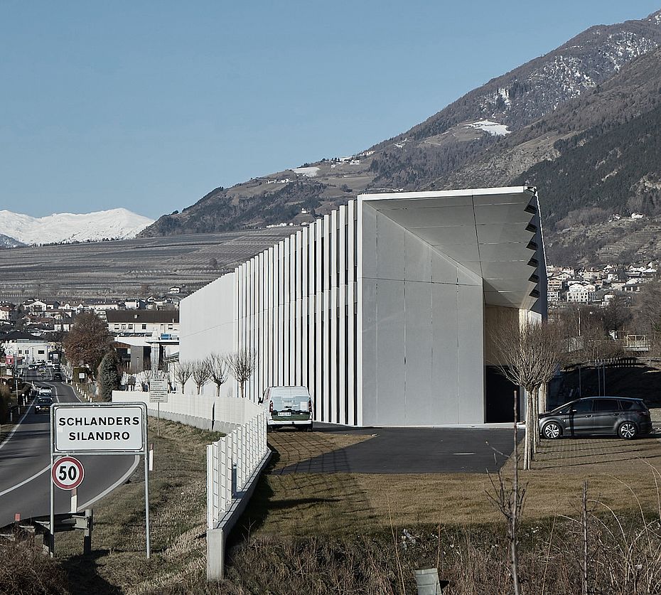 Edificio con struttura a lamelle all'ingresso del paese di Silandro davanti a scenario montano